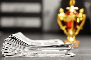 Newspapers stacked in pile and golden trophy cup, concept for winning award in business        