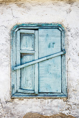 Vintage background from fragment of an old adobe wall with wooden blue window