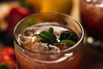 Bonito cóctel con zarzamoras, fresas y hojas de menta en un bonito vaso de vidrio sobre un fondo de madera