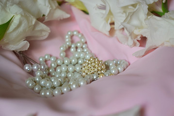Jewelry in white pearls and the flowers are on a light colored cloth.