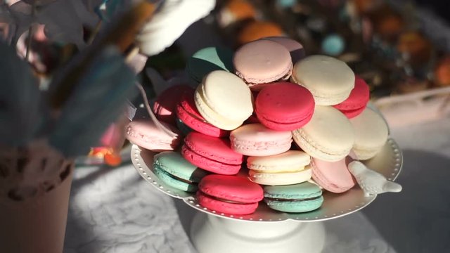 Dessert stand with colorful tasty macarons at wedding table. Birthday ceremony.
