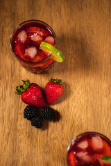 Bonito Cóctel con fresas, zarzamoras y una rodaja de limón para adornar en un fondo de madera