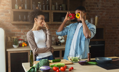 Happy african-american couple cooking and having fun in kitchen