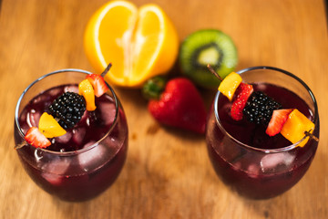 Bonito cóctel con fresas, kiwi, zarzamora y naranja en un fondo de madera