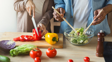 Black couple preparing vegetable salad together