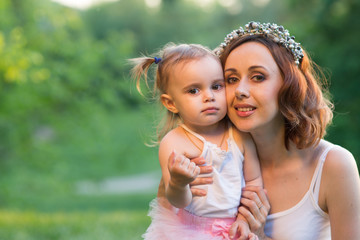 Mom and daughter are two years old sitting on the grass