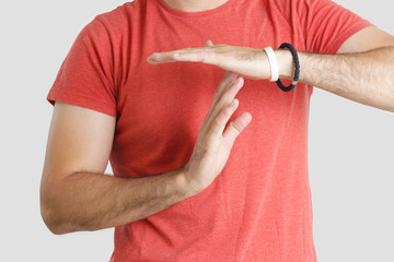 Young man in a red t shirt showing time out sign with his hands, studio shot, isolated 