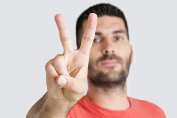 Studio portrait of young man showing peace sign