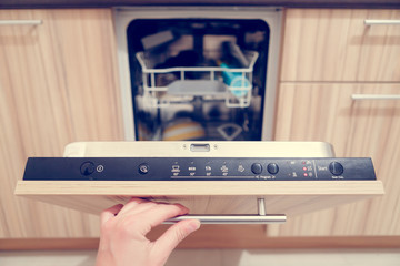 Picture of man's hand opening dishwasher with dirty dishes