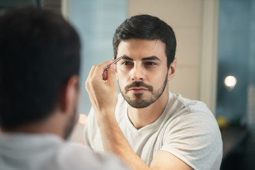 Latino Man Trimming Eyebrow For Body Care In Bathroom