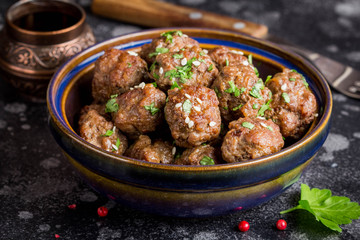 Beef meatballs in bowl with sauce, brown with sesame and parsley, tatsy snack