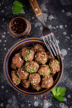 Beef meatballs in bowl with sauce, brown with sesame and parsley, tatsy snack