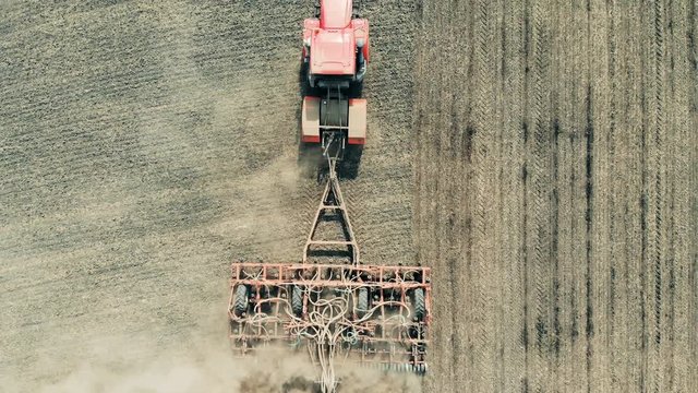 Agricultural plough seen from above is scattering field with seeds