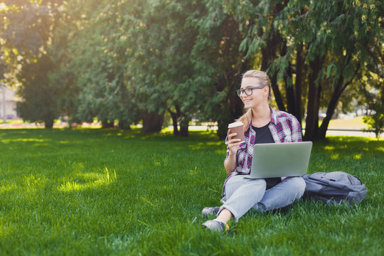 Happy young woman using laptop in park
