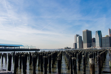 Fototapeta premium Some skyscrapers and water with wooden poles on a sunny day