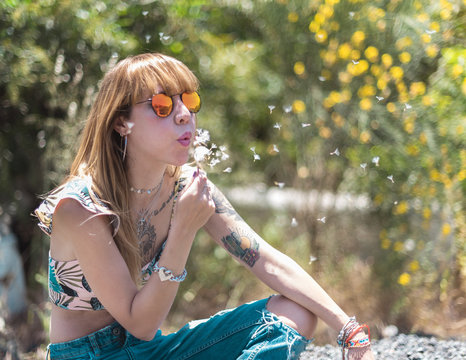 Pretty woman blowing on dandelion