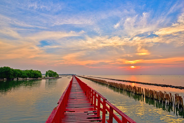 Sunrise and beautiful sky background at wooden red bridge over the sea.