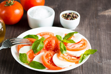 Close-up photo of caprese salad with ripe tomatoes, basil, buffalo mozzarella cheese. Italian and Mediterranean food concept. Fresh and healthy organic meal. Starter and antipasti. 