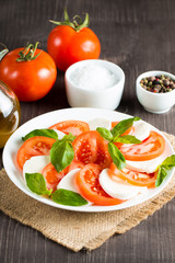 Close-up photo of caprese salad with ripe tomatoes, basil, buffalo mozzarella cheese. Italian and Mediterranean food concept. Fresh and healthy organic meal. Starter and antipasti. 