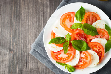 Close-up photo of caprese salad with ripe tomatoes, basil, buffalo mozzarella cheese. Italian and Mediterranean food concept. Fresh and healthy organic meal. Starter and antipasti. 