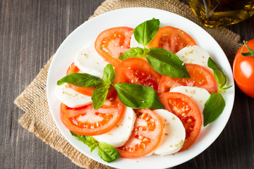 Close-up photo of caprese salad with ripe tomatoes, basil, buffalo mozzarella cheese. Italian and Mediterranean food concept. Fresh and healthy organic meal. Starter and antipasti. 