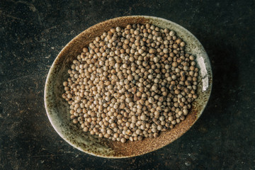 White peppercorns on a bowl with rustic background