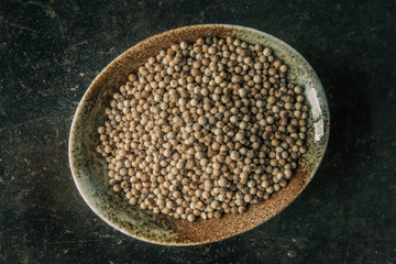 White peppercorns on a bowl with rustic background