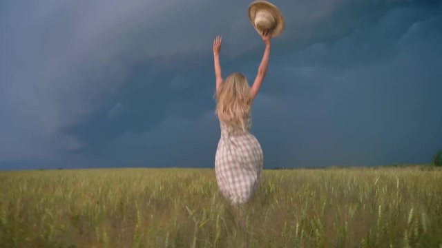 Silhouette of young beautiful inspired girl is running in field in rainy day, freedom concept