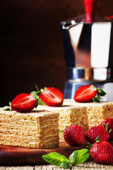 Traditional russian honey cake decorated with strawberries and green mint, old wooden background, selective focus