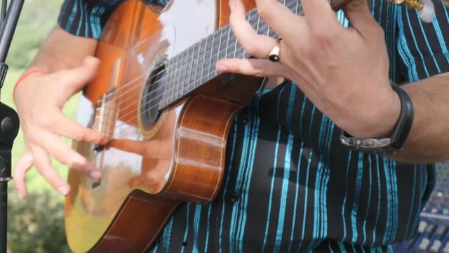 closeup detail of hand playing compas gipsy technique on folk guitar outdoor summer festival