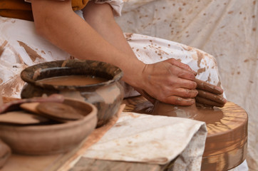 Close-up of female hand of medieval craftsman potter preparing clay - moistens and kneads the clay before work