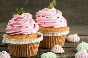 Closeup of cupcakes with vanilla, berries, pink and white cream, chocolate and sprinkles on wooden background. Selective focus. Sweet dessert tasty food concept muffin.