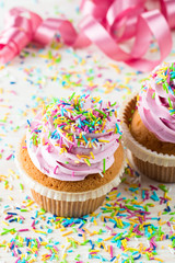 Closeup of cupcakes with vanilla, berries, pink and white cream, chocolate and sprinkles on wooden background. Selective focus. Sweet dessert tasty food concept muffin.