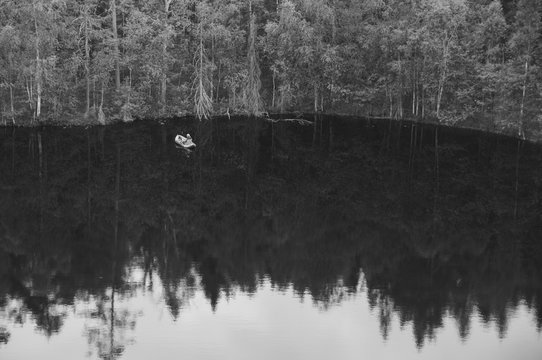 Black and white image of a fisherman on a forest lake