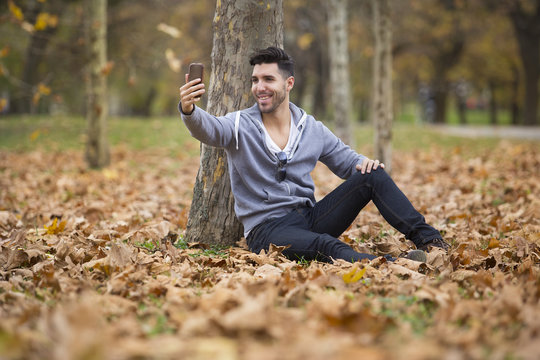 Handsome man in nature reading a book. Autumn leaves. Copy space