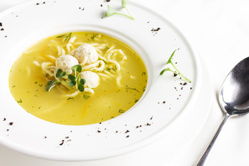 Chicken soup with meatballs and noodles in white table