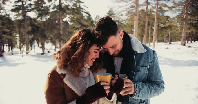 Romantic couple in love drinking hot chocolate in snowy forest