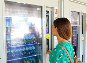Young female backpacker tourist choosing a snack or drink at vending machine in Venice, Italy....
