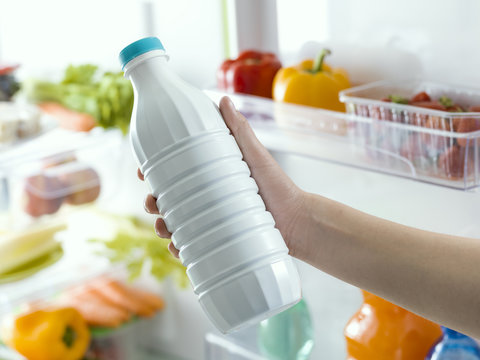 Woman taking a bottle of milk from the fridge
