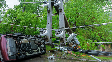 Electricity poles fall because of storms. damaged car