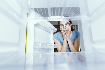 Desperate woman looking into her empty fridge