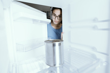 Sad woman looking into her empty fridge
