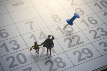 Parent and kid going to school with pinned calendar.