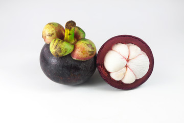 Isolated tropical fruits. One whole mangosteen and another cut in half isolated on white with clipping path