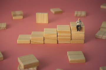 Businessman sipping coffee on top of wood ladder.