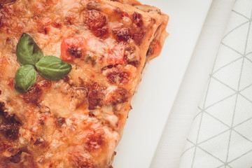 Homemade Lasagna with Minced Beef, Tomato Sauce and Fresh Basil on White Plate