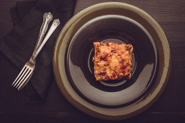 Traditional Italian Lasagna With Minced Beef, Tomato Sauce and Green Basil on Dark Plate