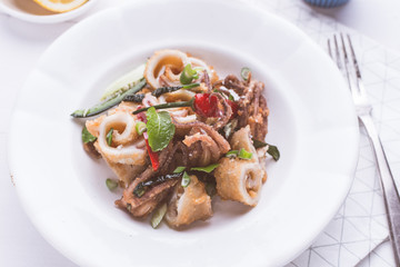 Fresh Fried Squids Calamari, Red Hot Chili Pepper and Green Mint Leaves on White Plate