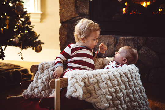Brothers in Christmas Sled by Fireplace