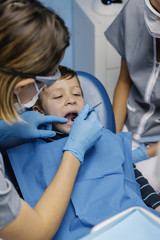 Dentists with a patient during a dental intervention to boy.